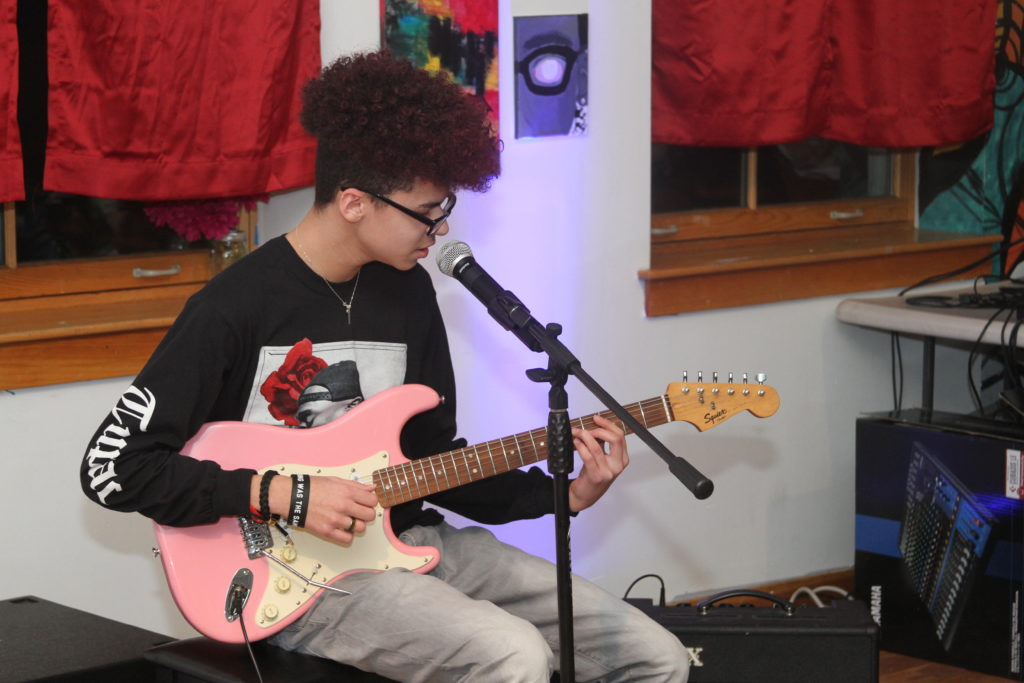 A student plays guitar during a monthly Open Mic