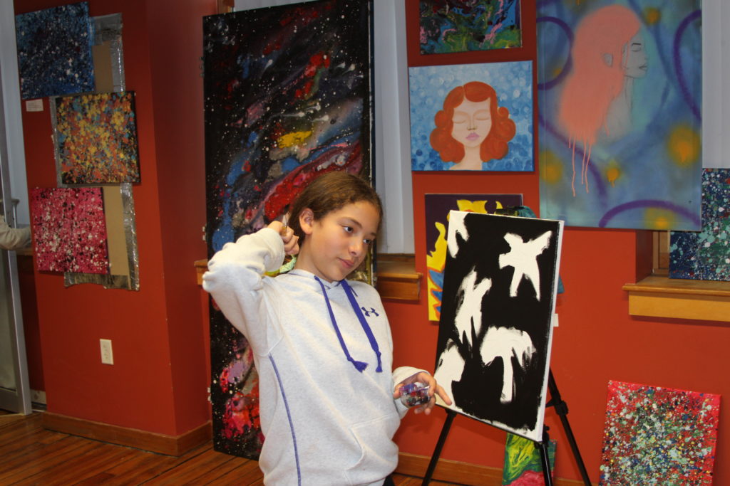 Young member stands in front of her original artwork